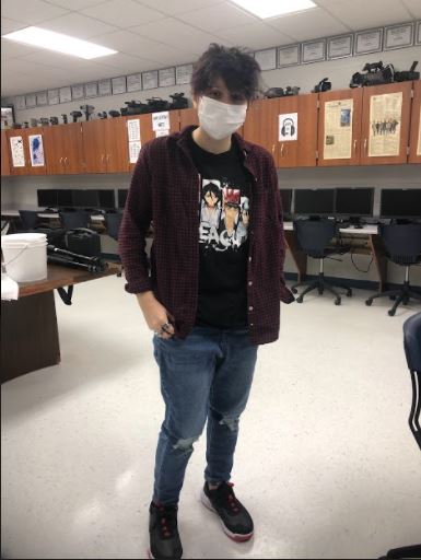 Junior Ryan Pasche wears a red flannel, a graphic t-shirt, and ripped jeans.