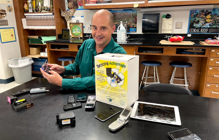 Mr. Walker poses with the variety of electronics that he has collected from students.