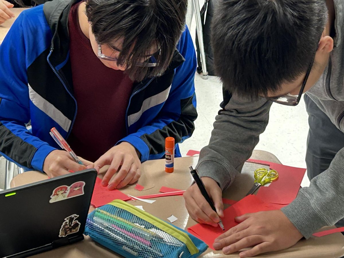 Two students crafting red envelopes