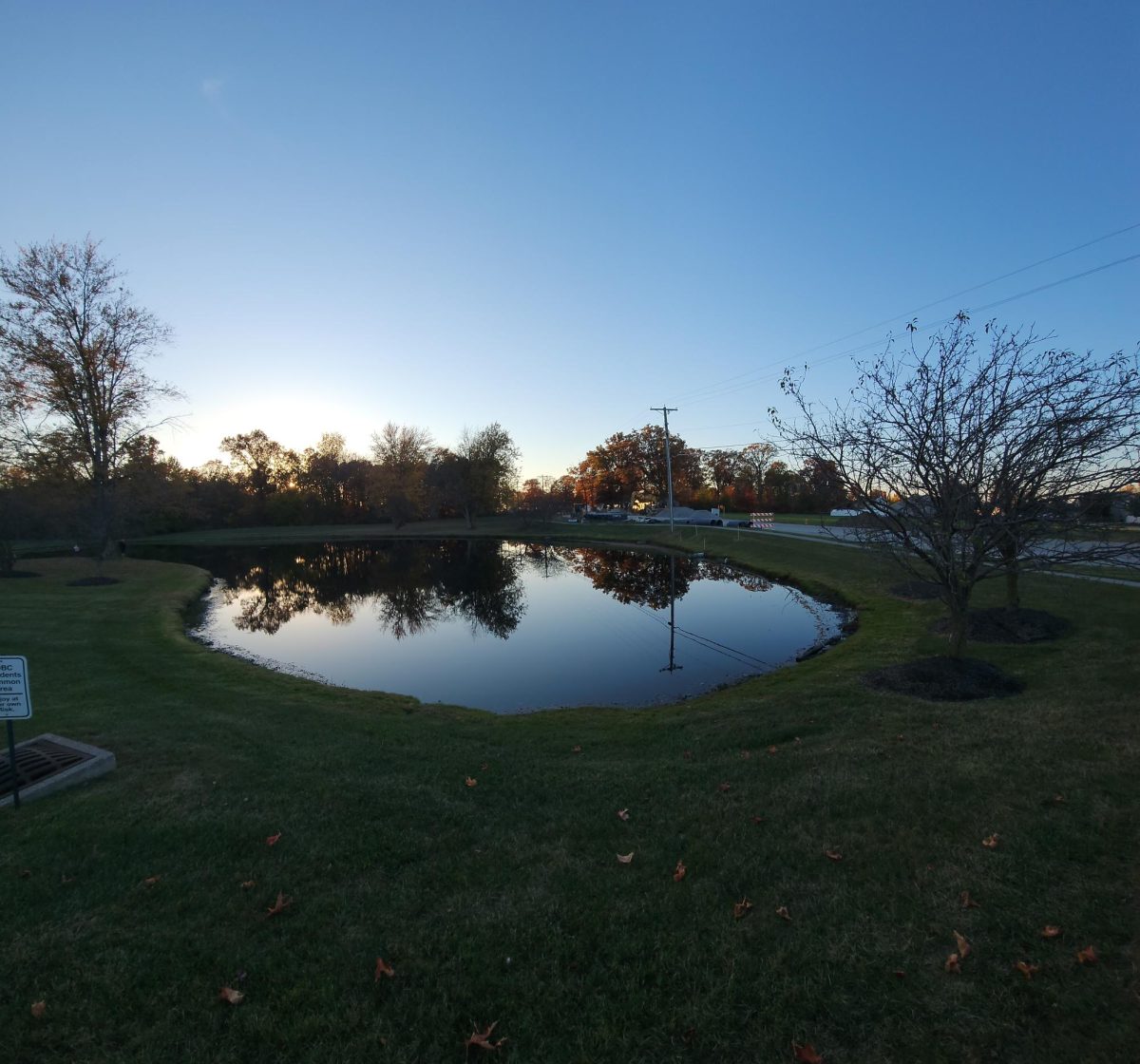 Panoramic picture of fall sunset on pond next to Carroll road. Piles of gravel stand vacant in the background on the torn up road.