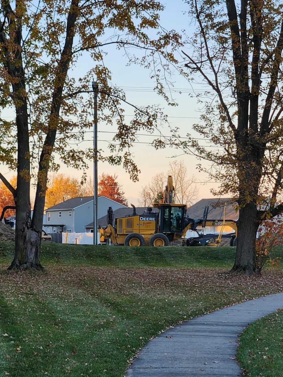 Second John Deere construction vehicle seen through trees with their leaves changed and partially fallen along path facing Carroll Road. Beautiful walk through trees obstructed by bulky construction.