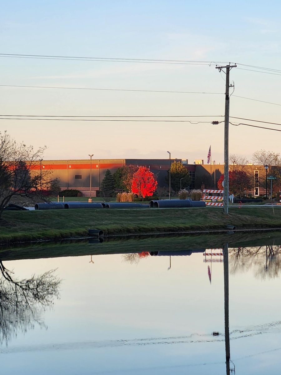 Culverts and barricades on road between pond and Pathway Church. Powerlines stand blocking the colors of the sky.